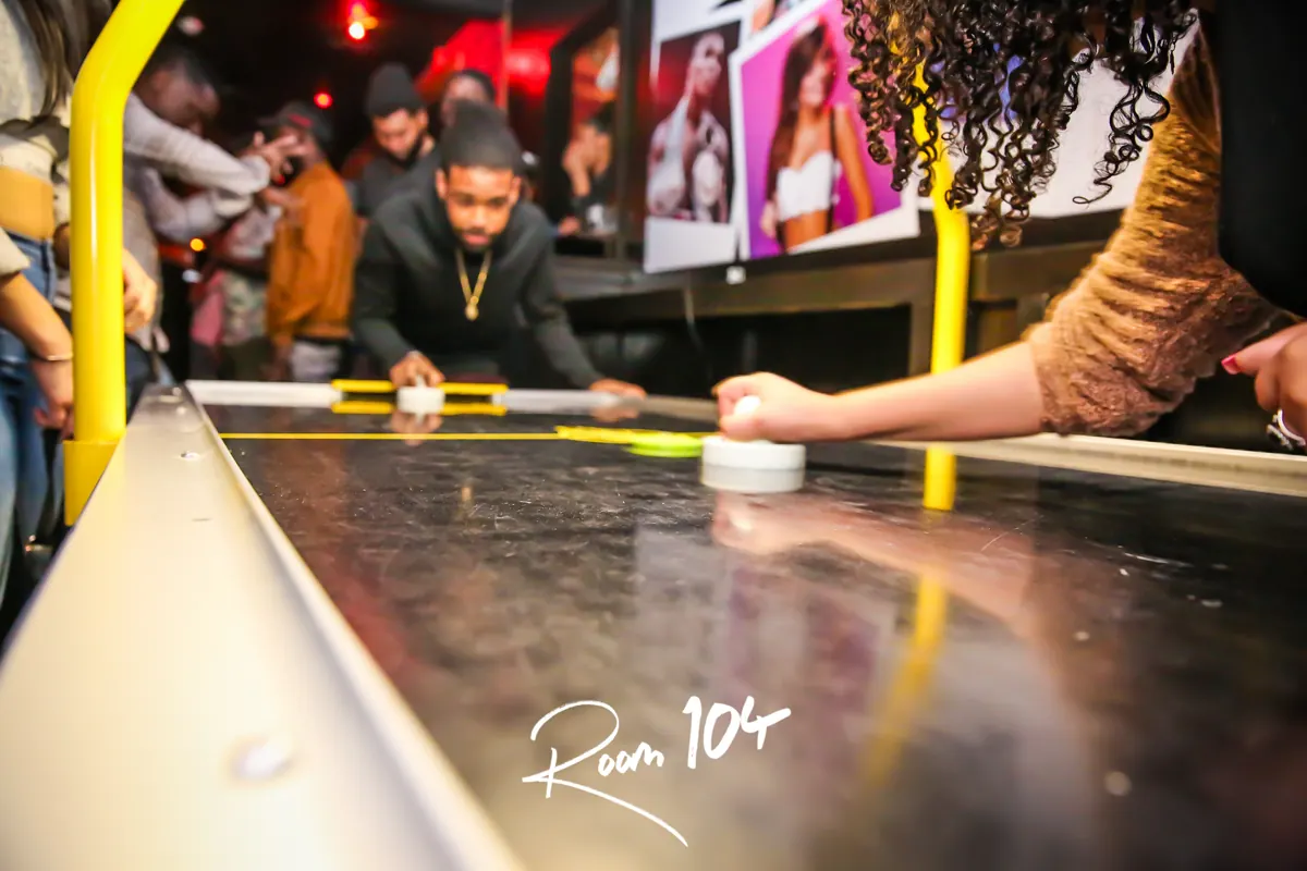 Friends playing air hockey at Room 104